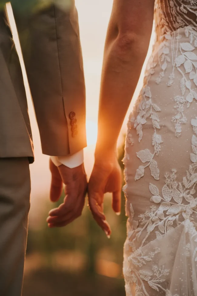 Bride and groom hands with the sun shining through
