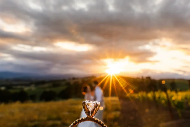 The bride and groom and a wedding ring close up with a spectacular sunset beyond